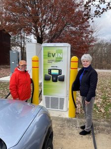 Two people standing in front of electric vehicle charger