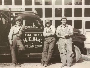 Historic photo of three men standing in front of a truck